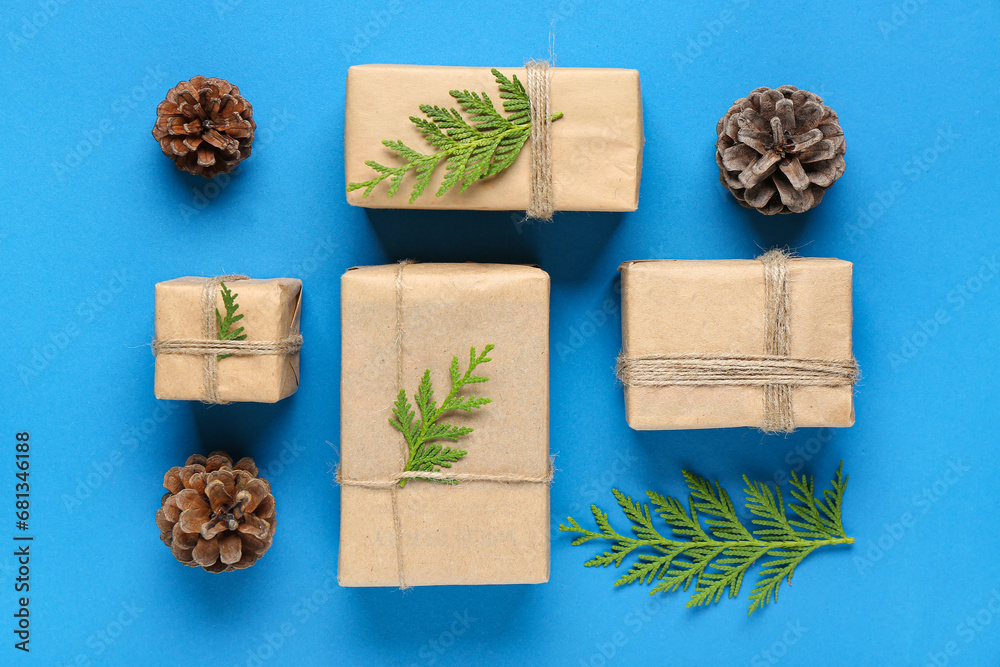 Pine cones with coniferous branches and Christmas gift boxes on blue background