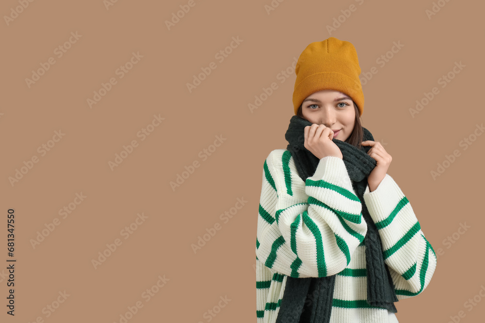 Young woman in winter clothes on brown background