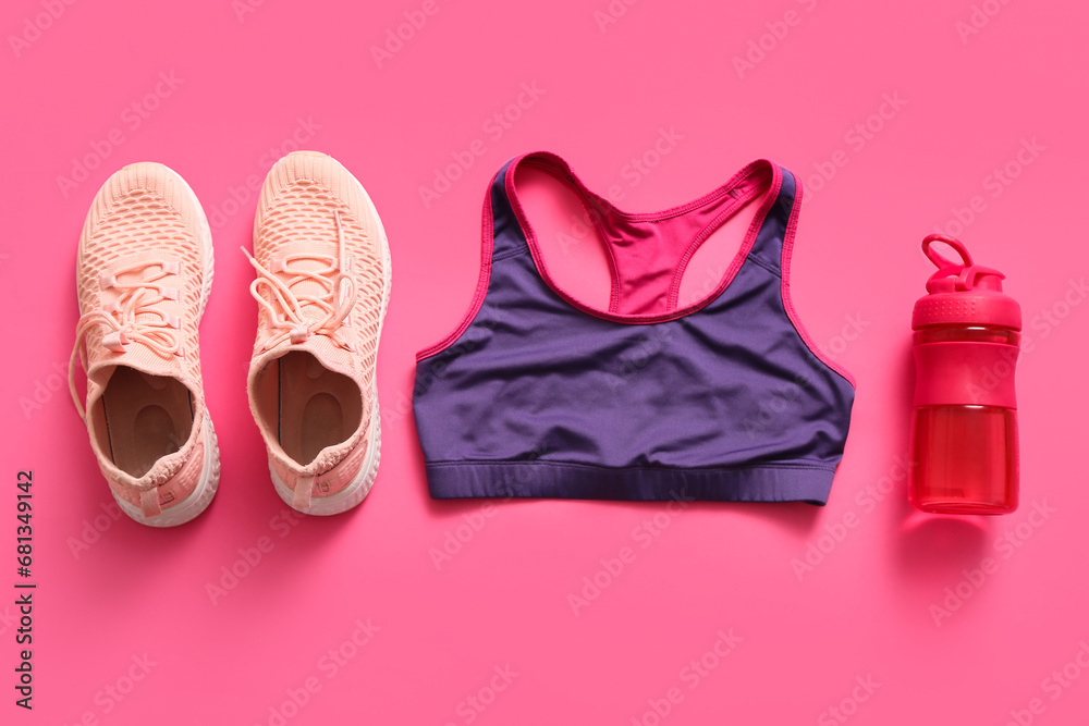 Sports bottle with top and sneakers on pink background