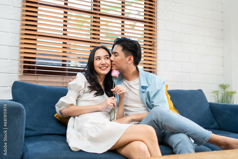 Asian young man surprise and give rose flower to beautiful girlfriend. 