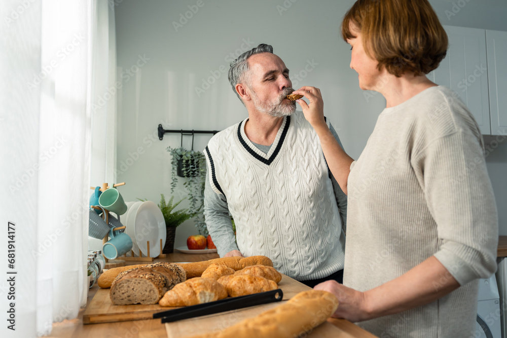 Caucasian senior elderly couple spend time together in kitchen at home. 