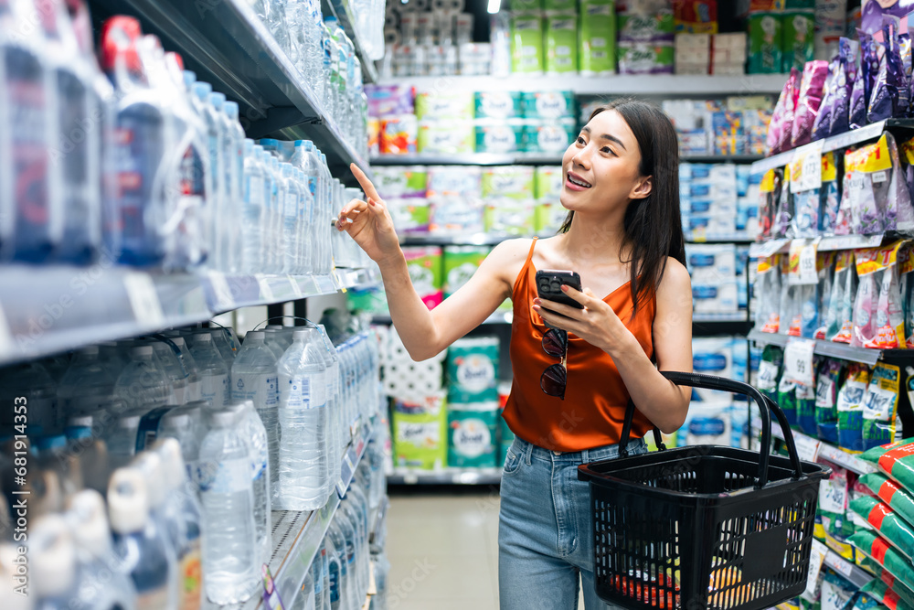 Asian young beautiful woman holding grocery basket walk in supermarket. 