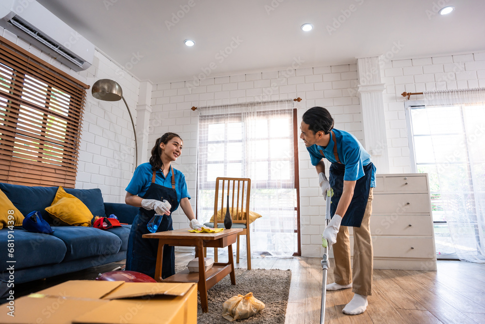 Asian young man and woman cleaning service worker work in living room.