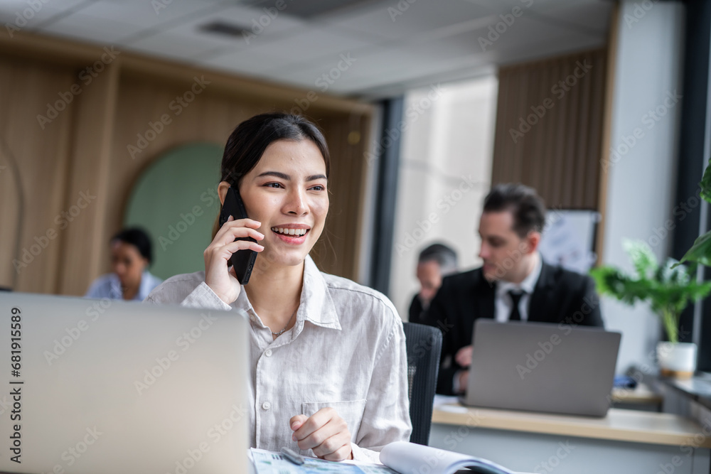 Asian happy businesswoman talking on smartphone and working in office. 